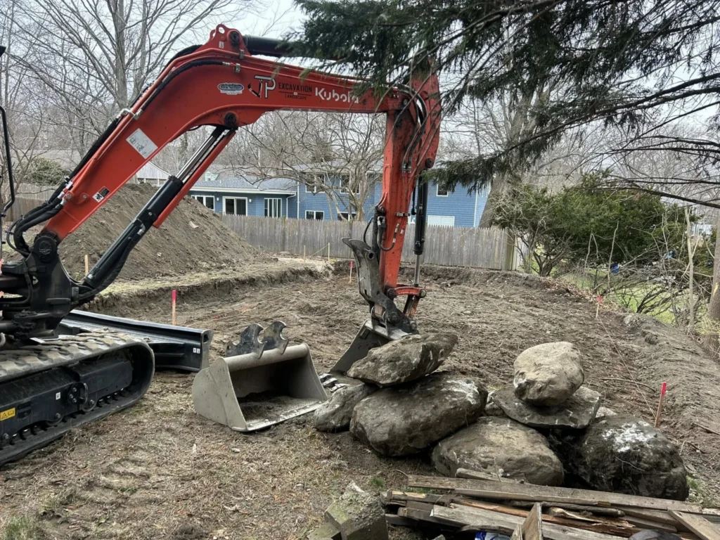 Kubota excavator working around large landscape boulders