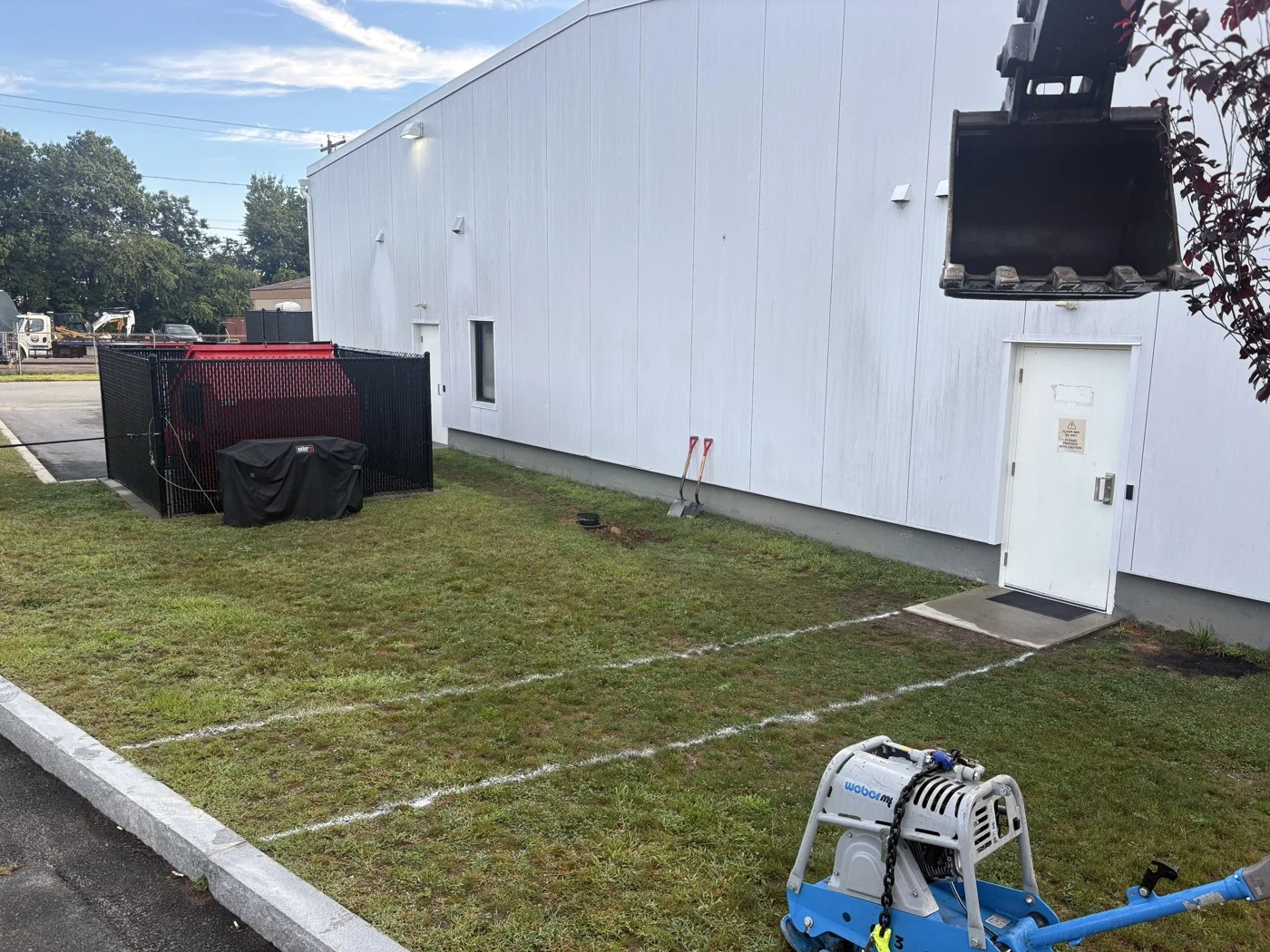Marked grass beside a building before drainage and walkway preparation