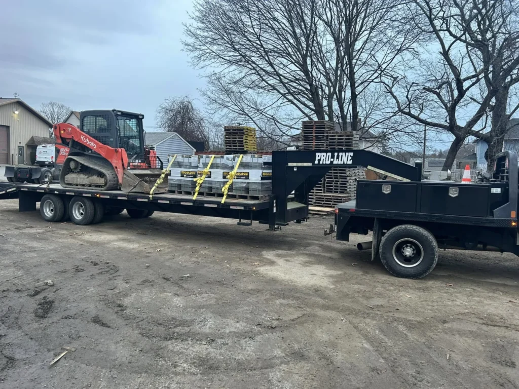 JP equipment trailer carrying a Kubota loader and attachments