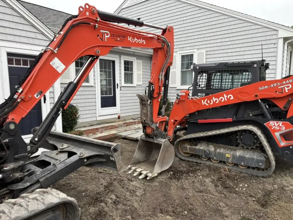 JP Excavation orange Kubota excavator and compact track loader outside a home
