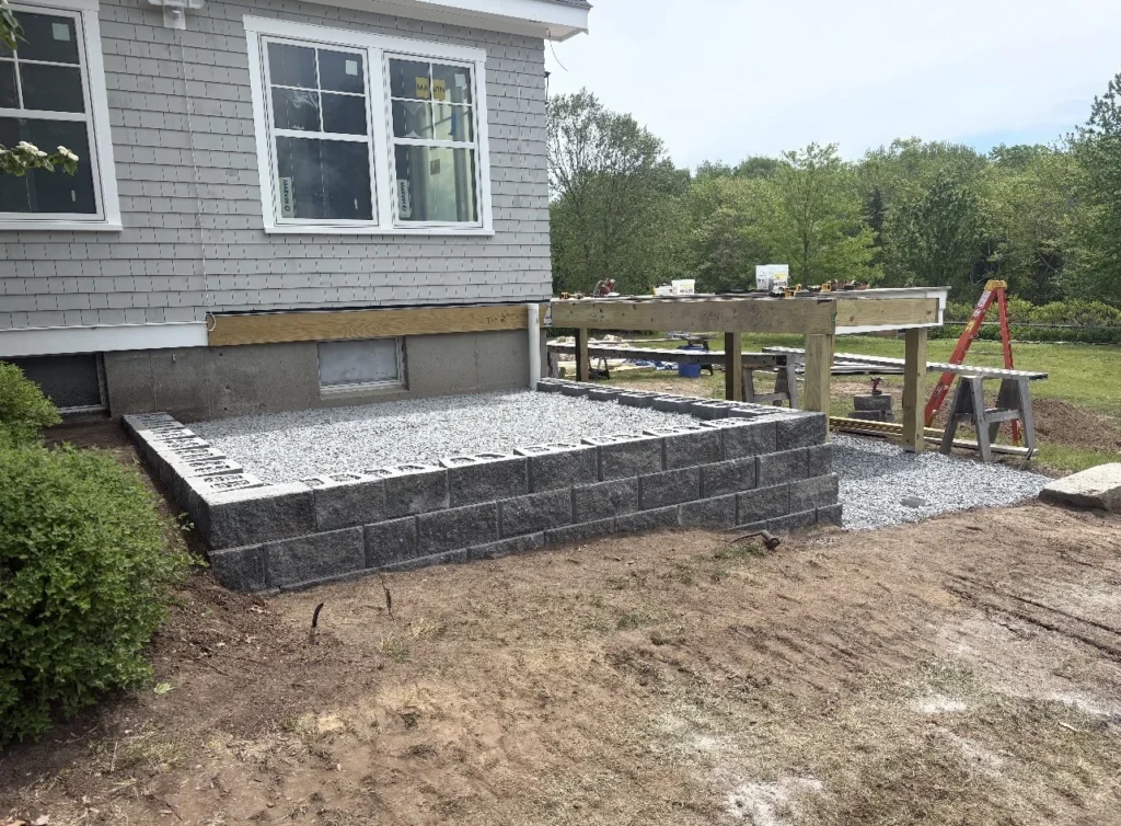 Finished straight block retaining wall beside a gray house