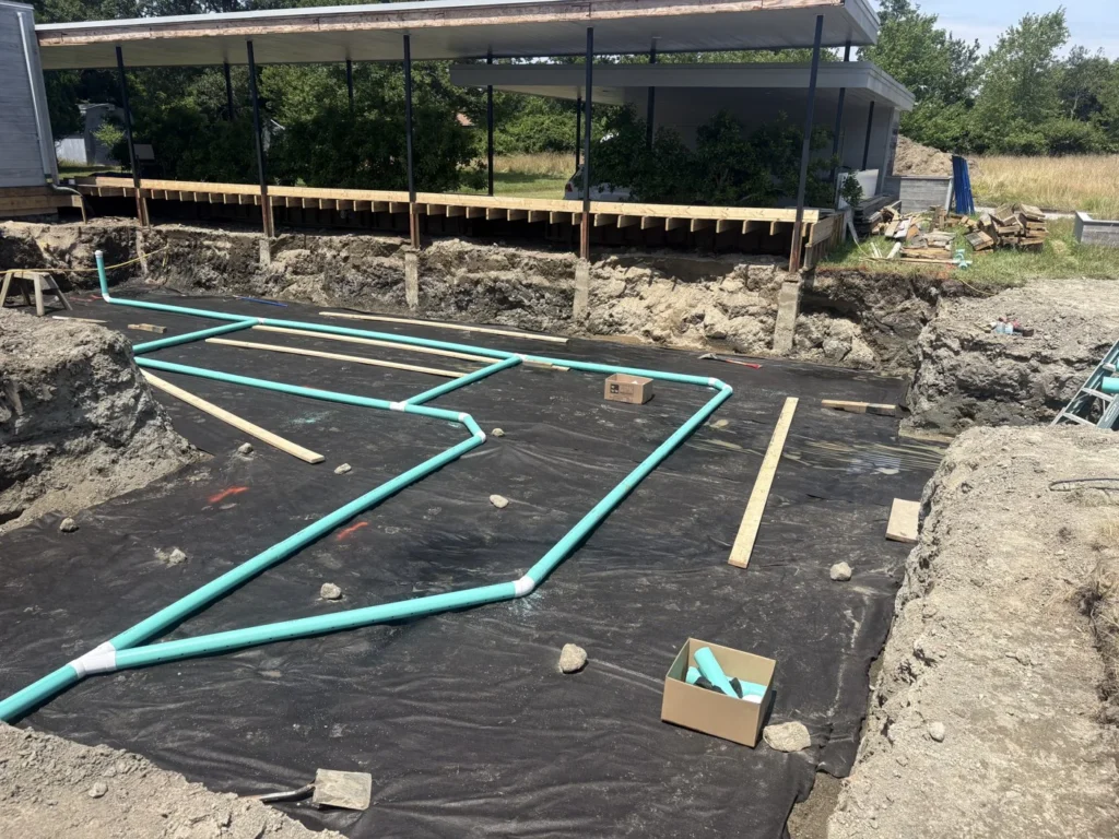 Green pipe installed across a prepared building foundation area
