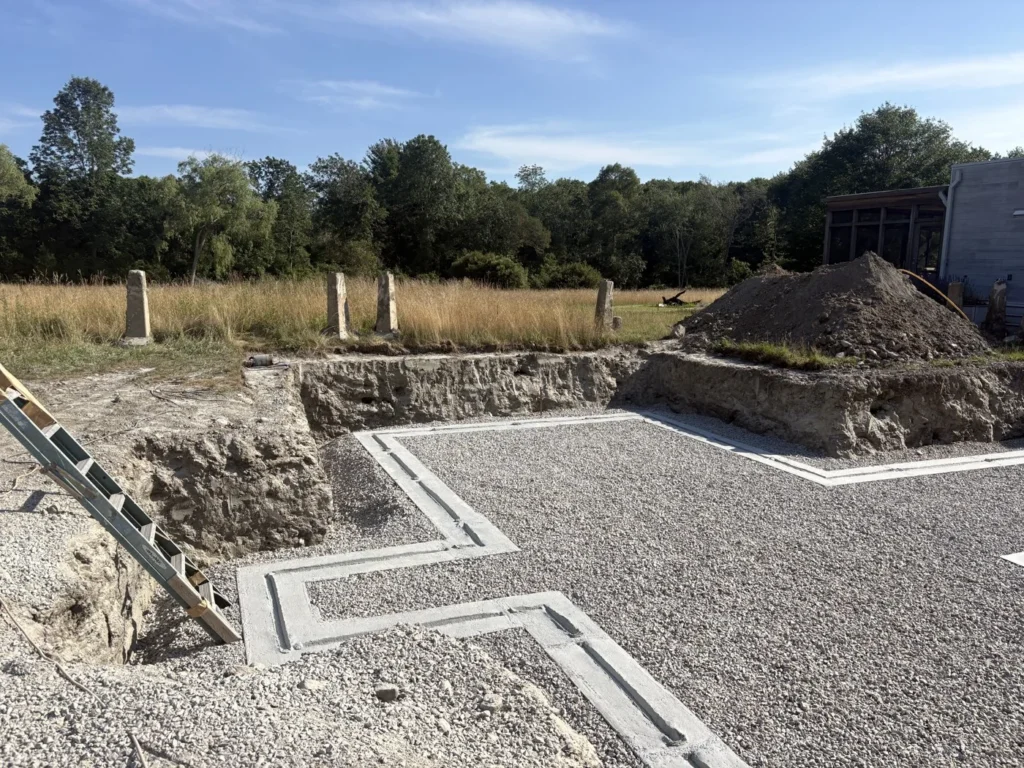 Foundation footings with a leveled aggregate base and perimeter piping