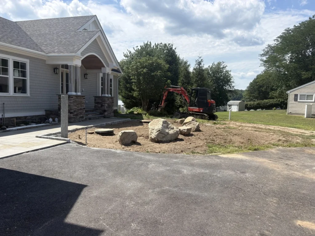 Excavator and boulder edging during residential landscape work