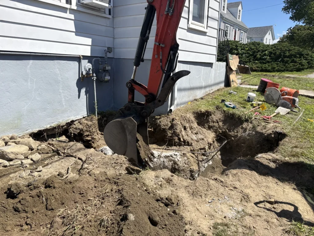 Compact excavator working beside a house for utility access