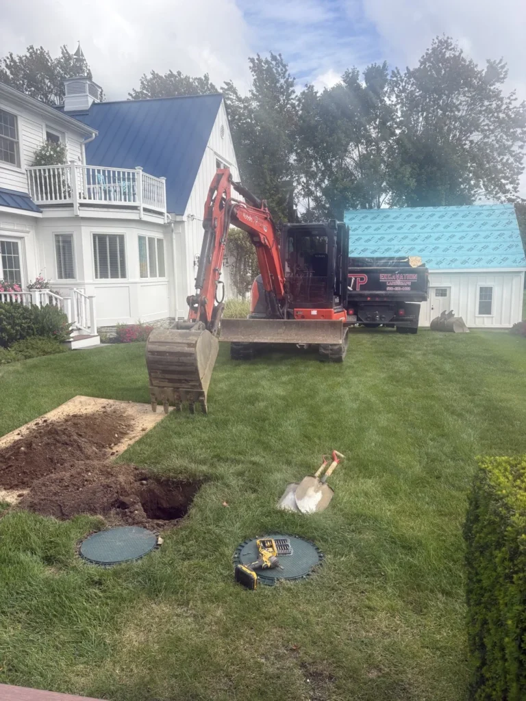 Kubota excavator near exposed septic access covers at a residential property