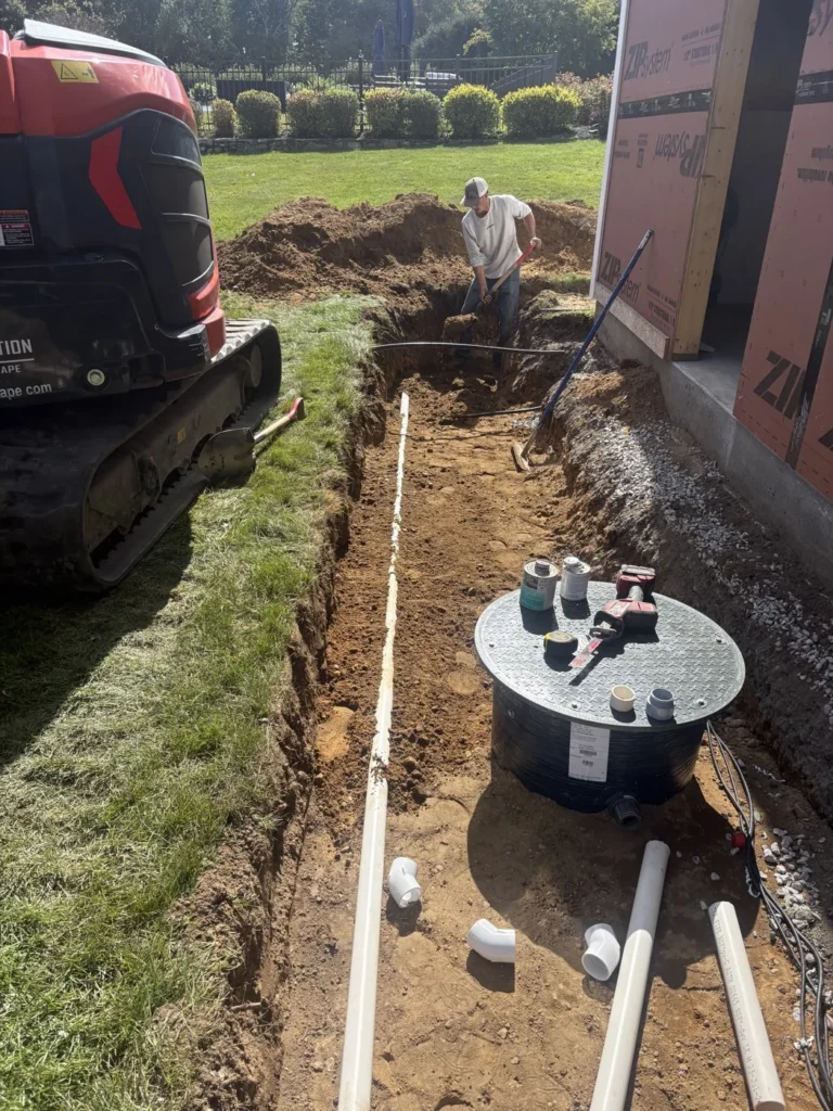 Underground tank and white pipework during excavation beside a home